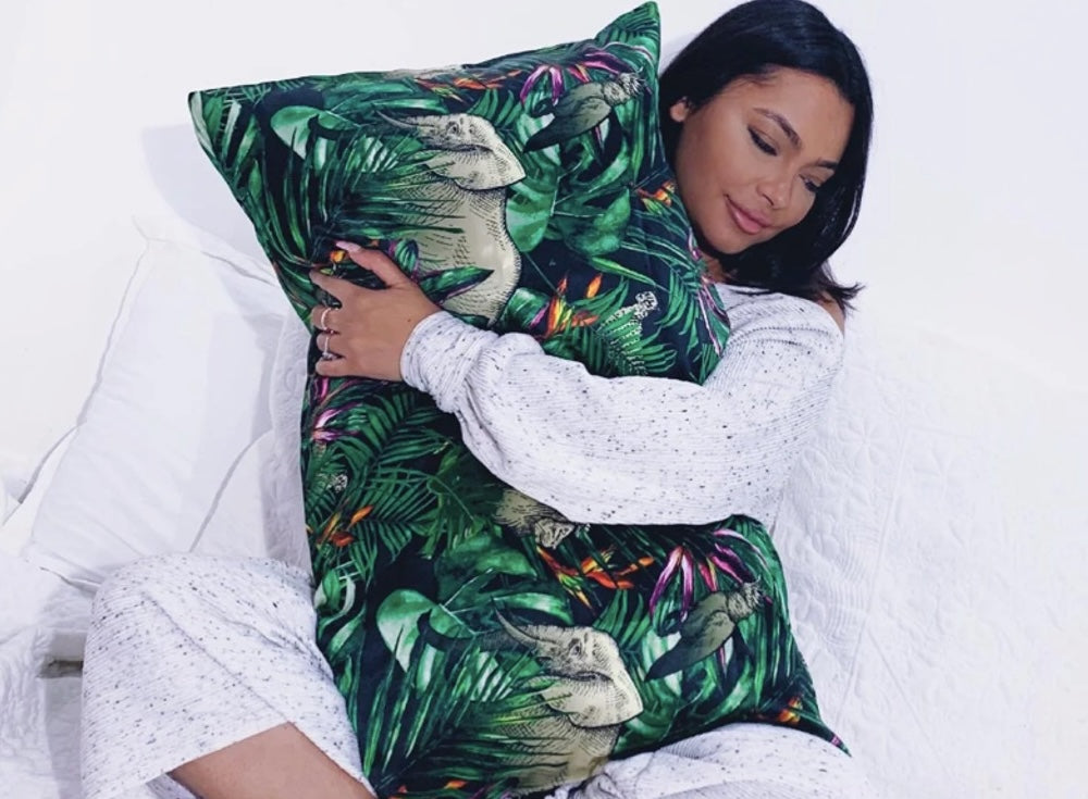 A person looking radiant while holding a pure silk pillowcase, the best option for hair and skin health