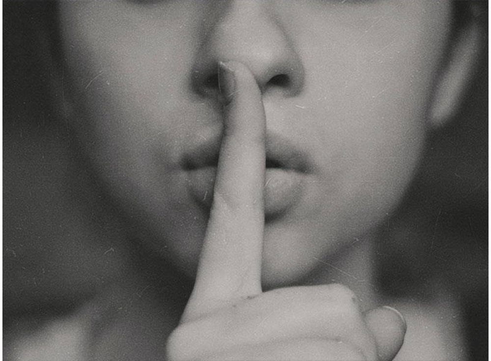 Black-and-white portrait of a woman holding a finger to her lips