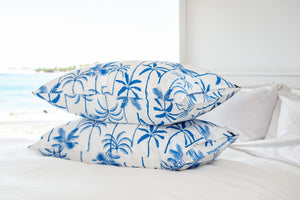 Two silk pillowcases stacked on top of each other with The Palms print in blue on Ivory background. 